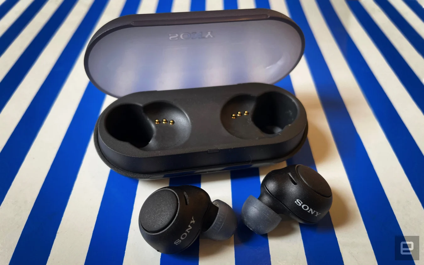 Black wireless earbuds and their charging case on a blue and white striped background.