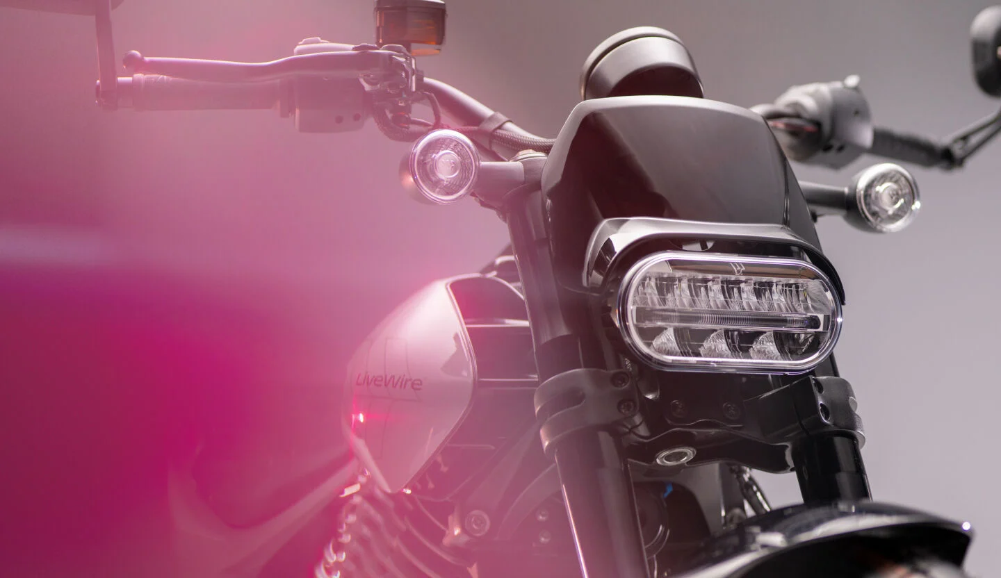 Marketing photo of the LiveWire S2 Del Mar e-motorcycle. Closeup of its front with a dramatic purple lens flare.