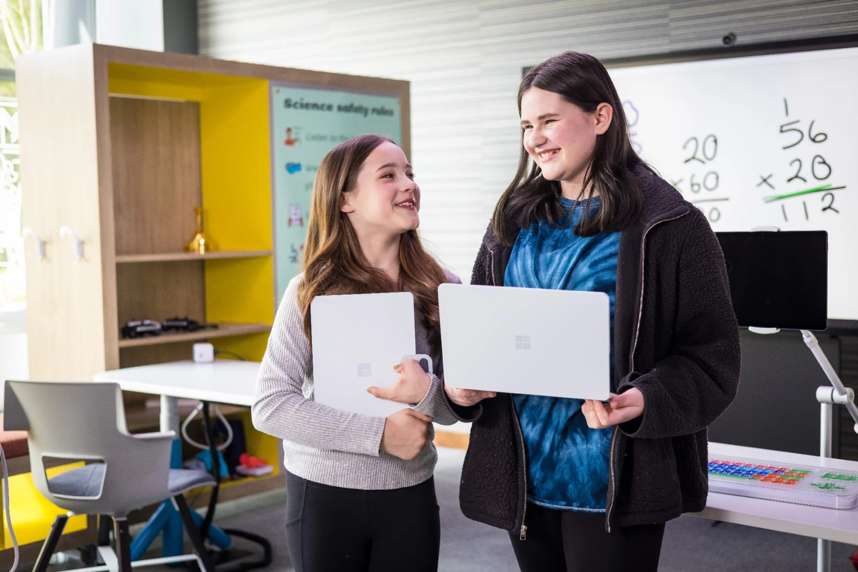 Two people in the classroom section of Microsoft's new Inclusive Tech Lab, both holding laptops in their hands.