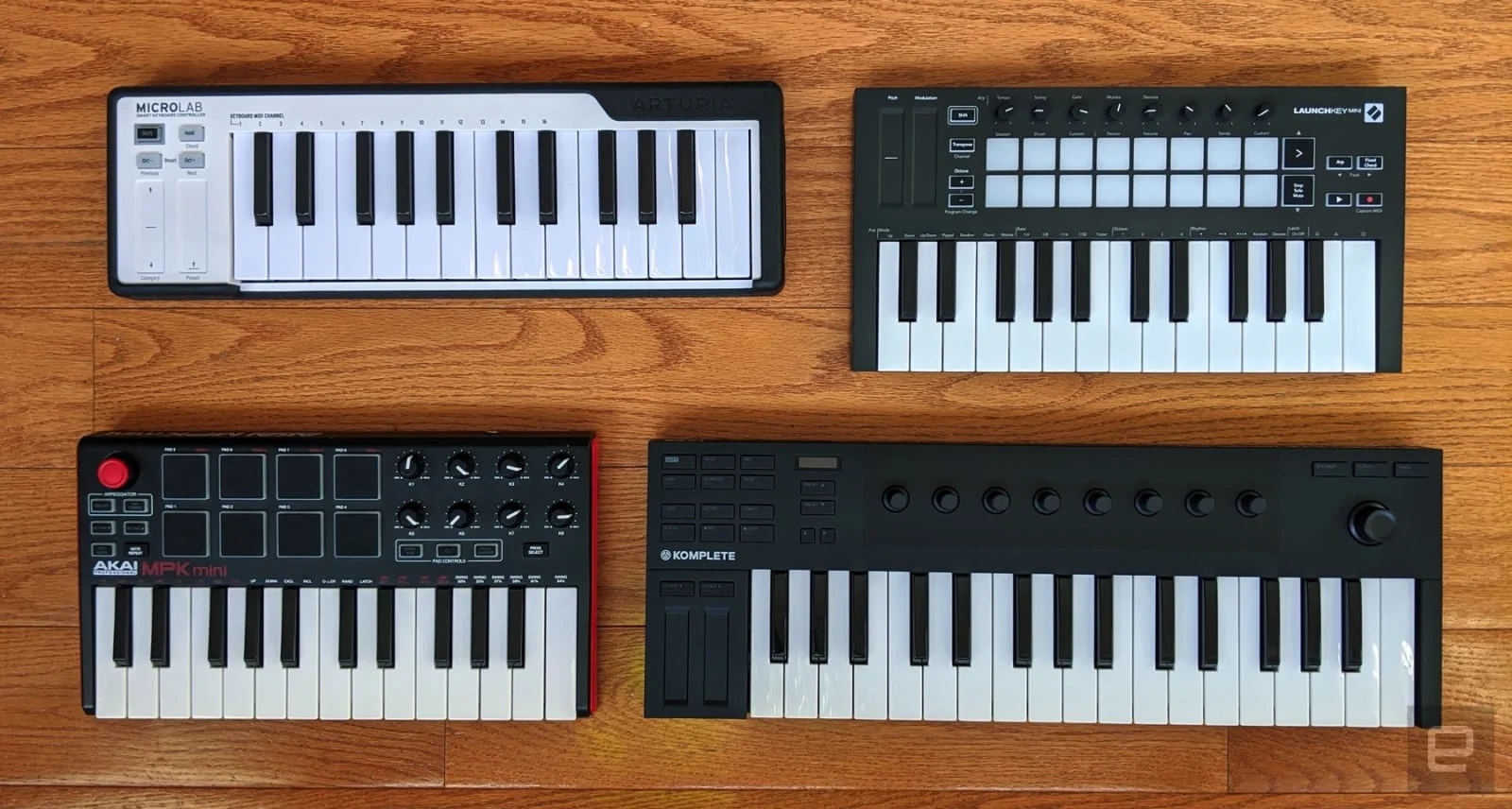 An overhead view of four different midi keyboards on a wooden desktop.