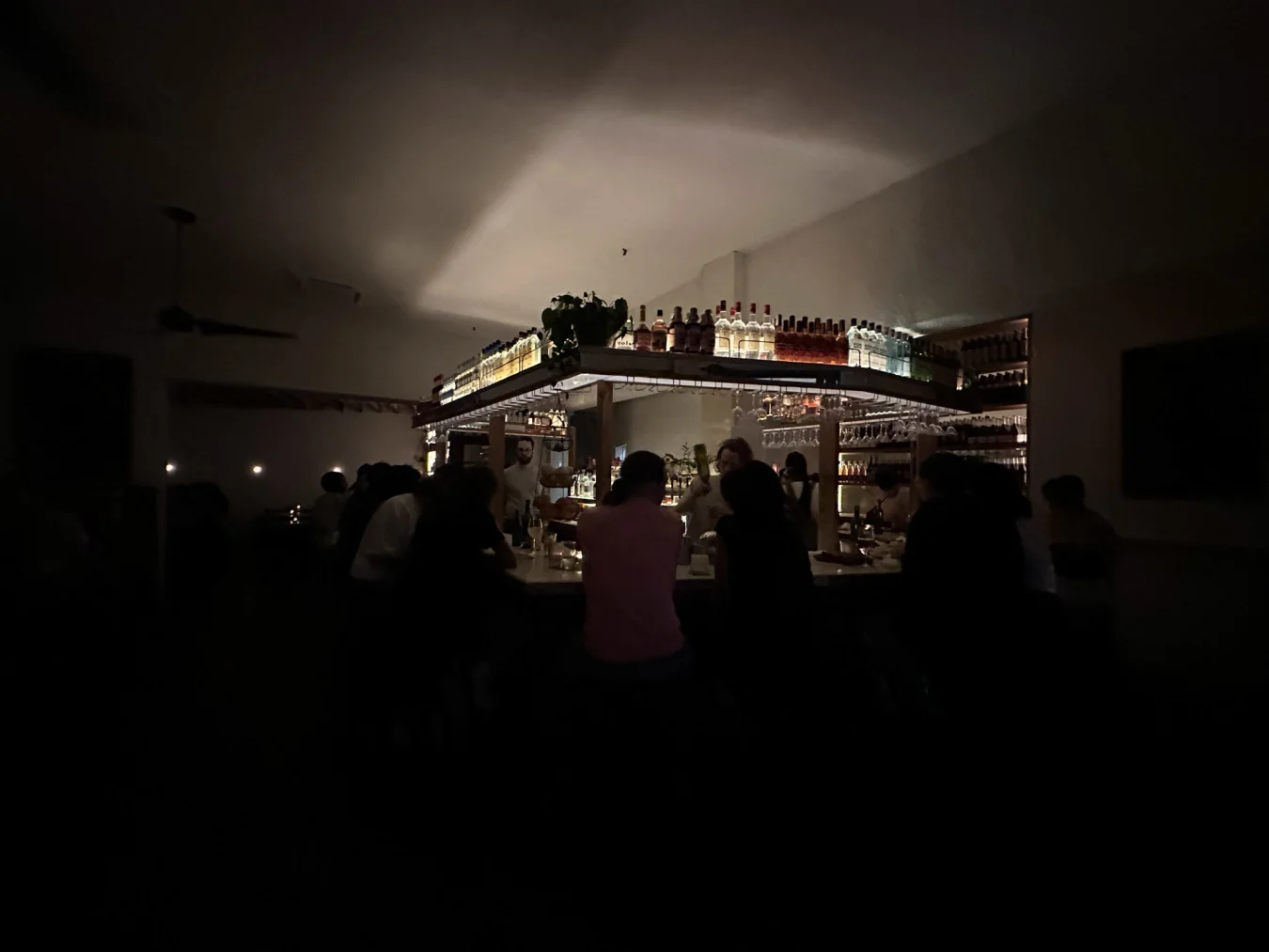 Ein Foto von der Weitwinkelkamera des iPhone 14 Pro von einer hellen Bar in einem dunklen Restaurant.