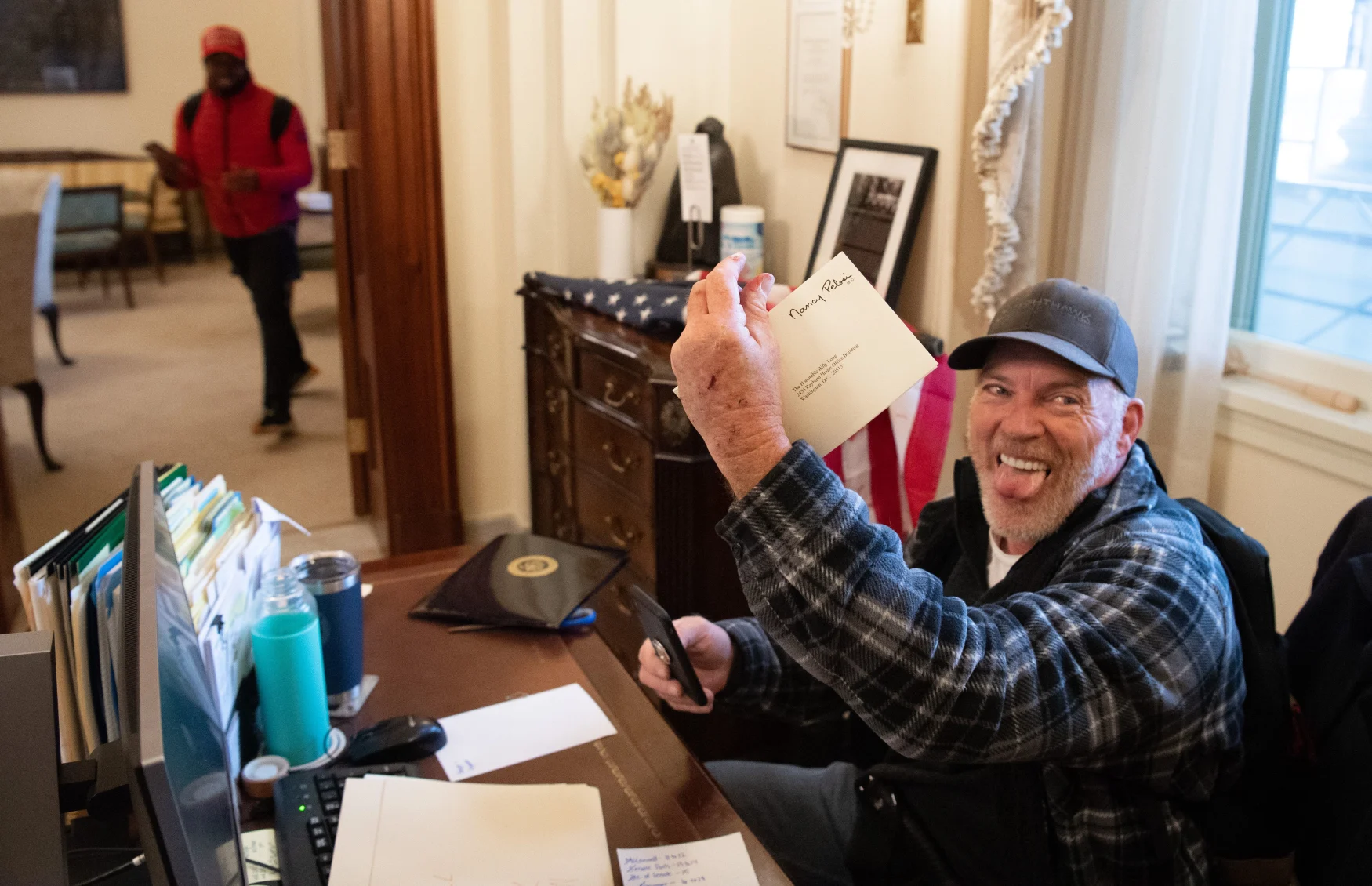 (FILES) Richard Barnett, a supporter of US President Donald Trump, holds a piece of mail as he sits inside the office of US Speaker of the House Nancy Pelosi after protestors breached the US Capitol in the US Capitol in Washington, DC, January 6, 2021. - Demonstrators breeched security and entered the Capitol as Congress debated the 2020 presidential election Electoral Vote Certification. (Photo by SAUL LOEB / AFP) (Photo by SAUL LOEB/AFP via Getty Images)