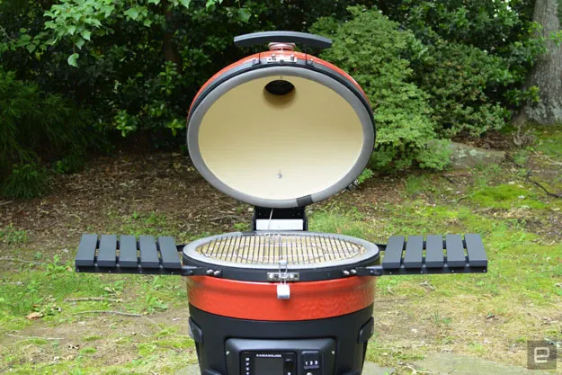 Image of a Konnected Joe smart grill with the lid open in a garden space.