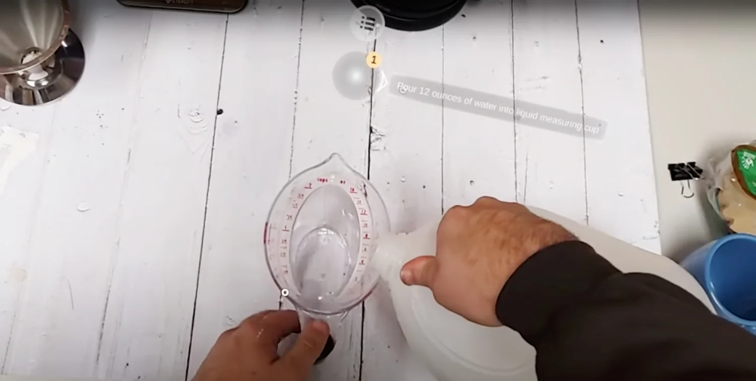 First person perspective of person pouring liquid from a plastic jug into a measuring cup.  AR instructions “Pour 12 ounces of water into a liquid measuring cup” are overlaid in their field of view.