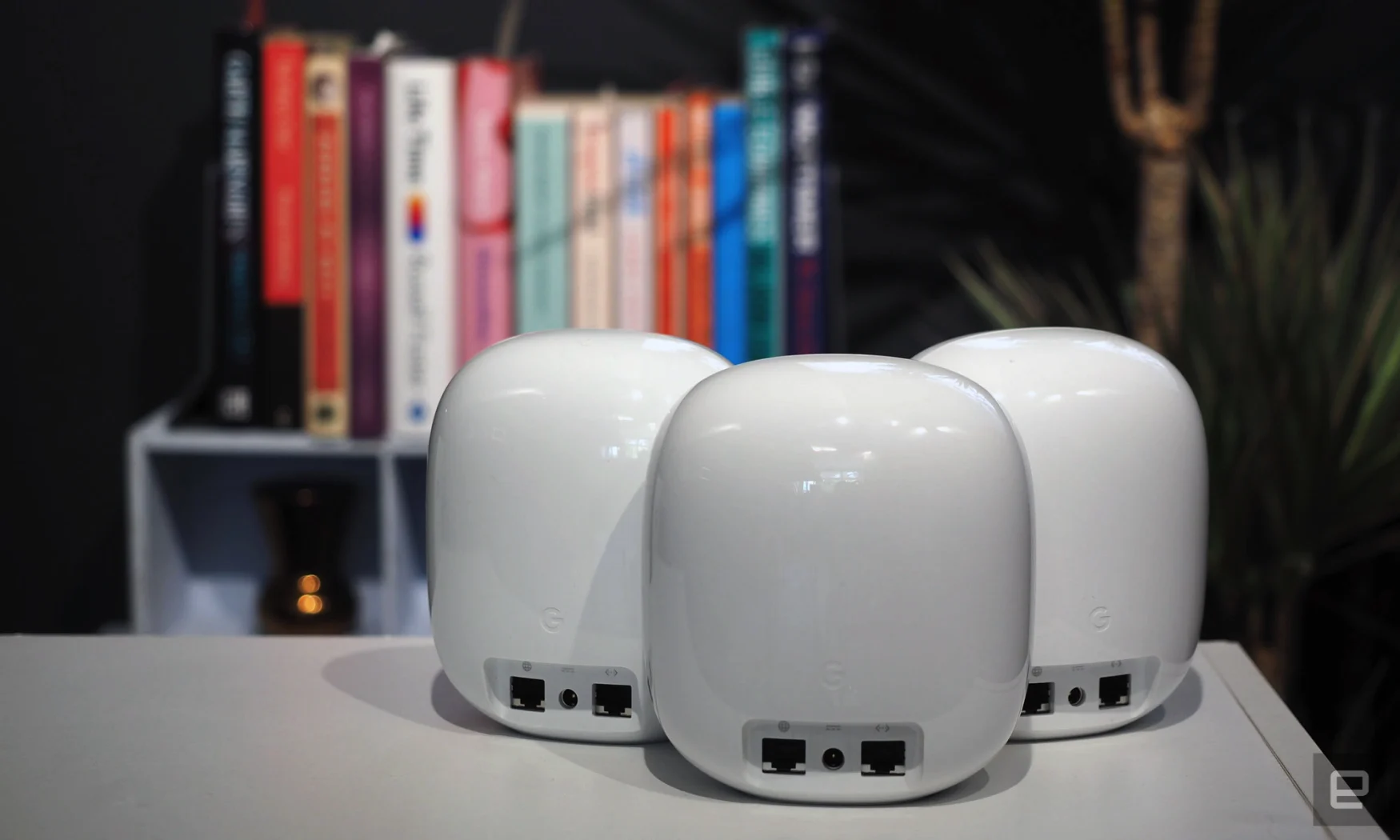 Image of three Nest WiFi Pro units, rear-on, in front of a blurred bookcase.