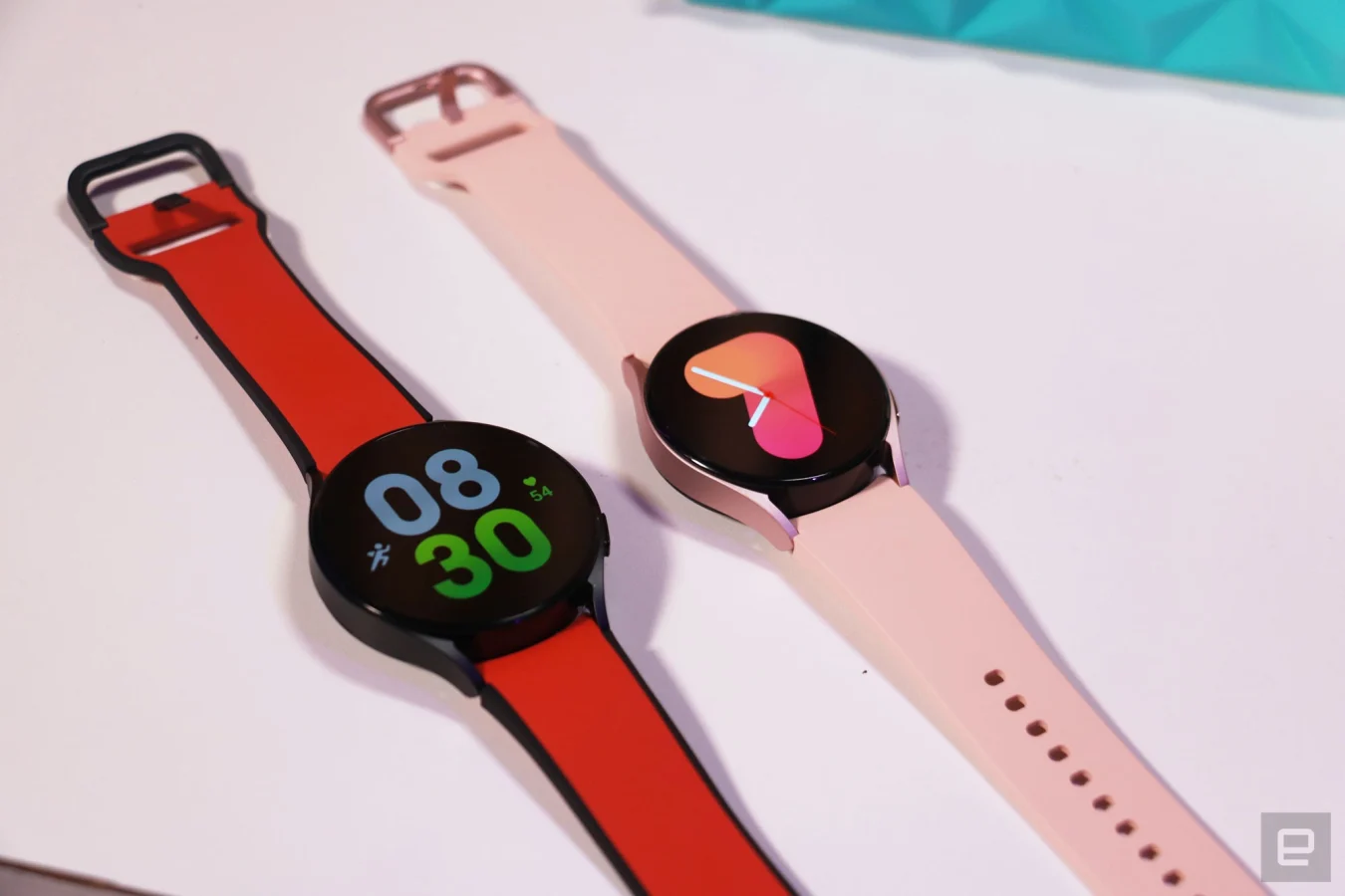Eine rote 44-mm-Galaxy Watch 5 und eine rosa 40-mm-Galaxy Watch 5 nebeneinander auf einem Tisch.