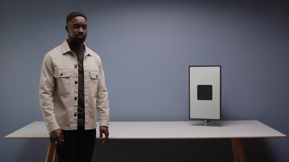An animation showing how Google's proposed interaction language works. This is an example of the Glance action, where a man looks at a display to his right, and its screen shows a black square reacting in response.