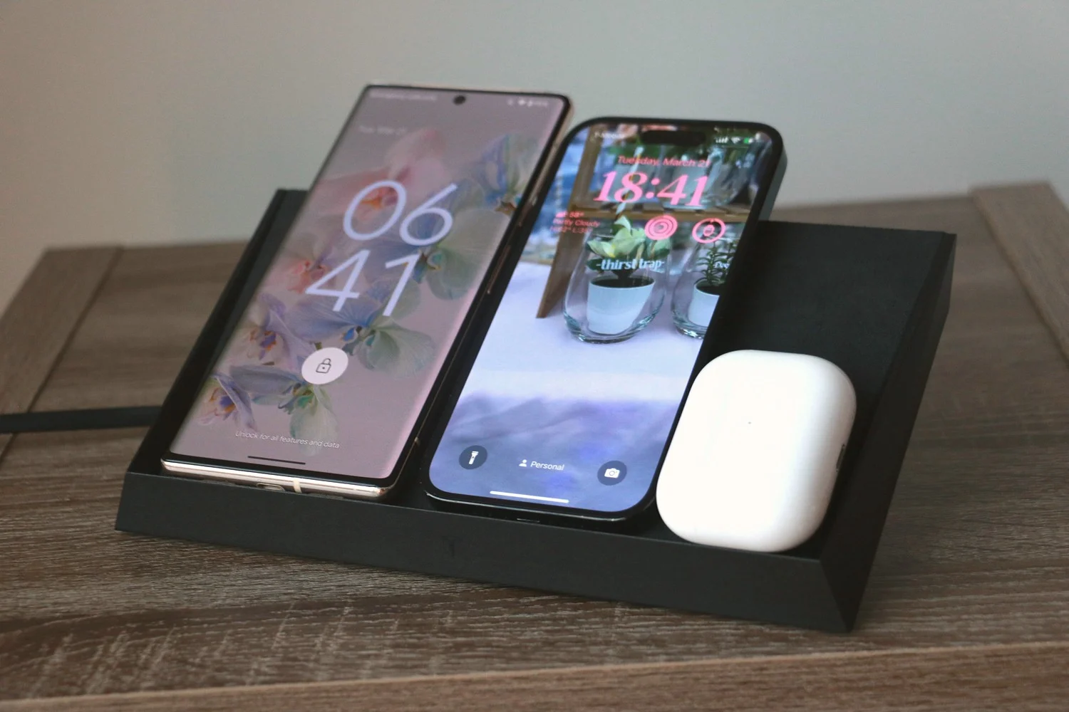 The Tesla Wireless Charging Platform with three devices on it. From left to right, they are a Pixel 6 Pro, iPhone 14 Pro and AirPods Pro 2.