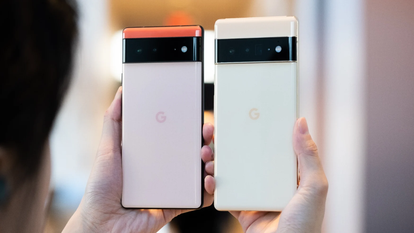 The Google Pixel 6 and 6 Pro held up in mid-air with their camera bars facing out.