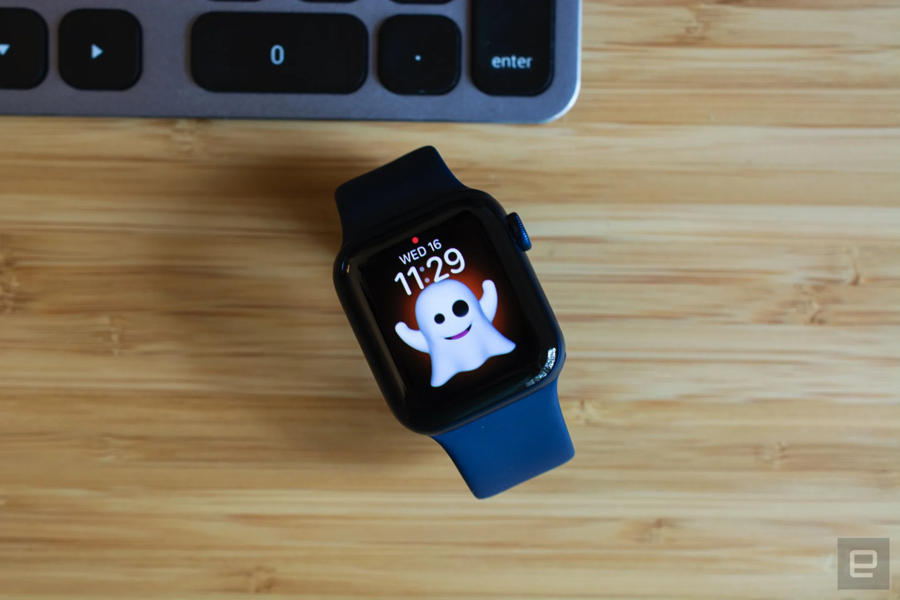 The Apple Watch Series 6 with a Memoji watch face sitting on a wooden table.