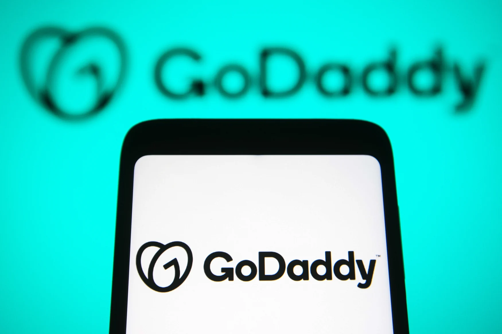 UKRAINE - 2021/11/22: In this photo illustration, the GoDaddy Inc. logo is seen on a smartphone and on the background. (Photo Illustration by Pavlo Gonchar/SOPA Images/LightRocket via Getty Images)