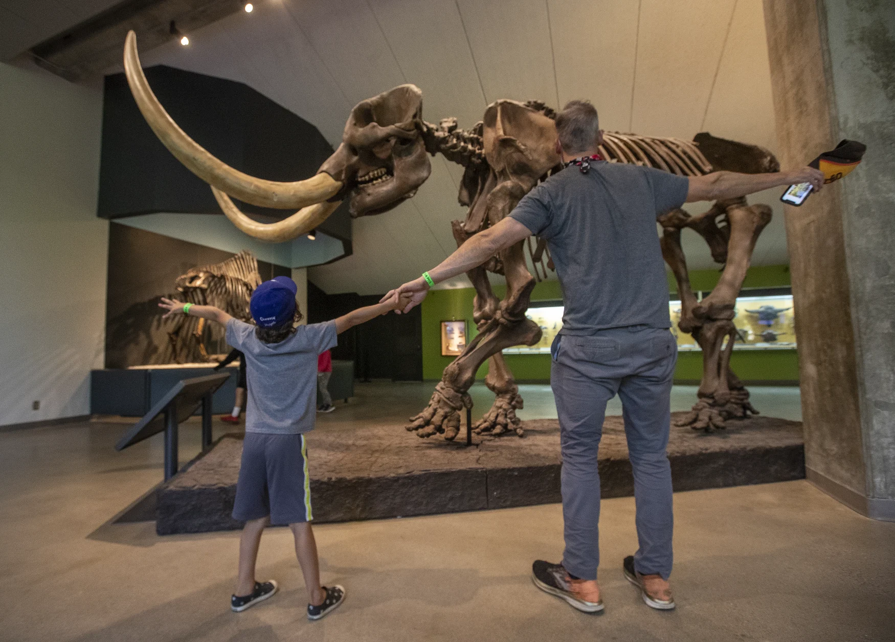 LOS ANGELES, CA - APRIL 08, 2021: Connor Matlen, 6, and his father Logan, 45, of Hawthorne, spread their arms to try and cover the length of the American mastodon on display at The La Brea Tar Pits in Los Angeles that re-opened to the public after being closed for over a year due to the COVID-19 outbreak.  The American mastodon existed from 2 million to 10,000 years ago.  (Mel Melcon/Los Angeles Times via Getty Images)