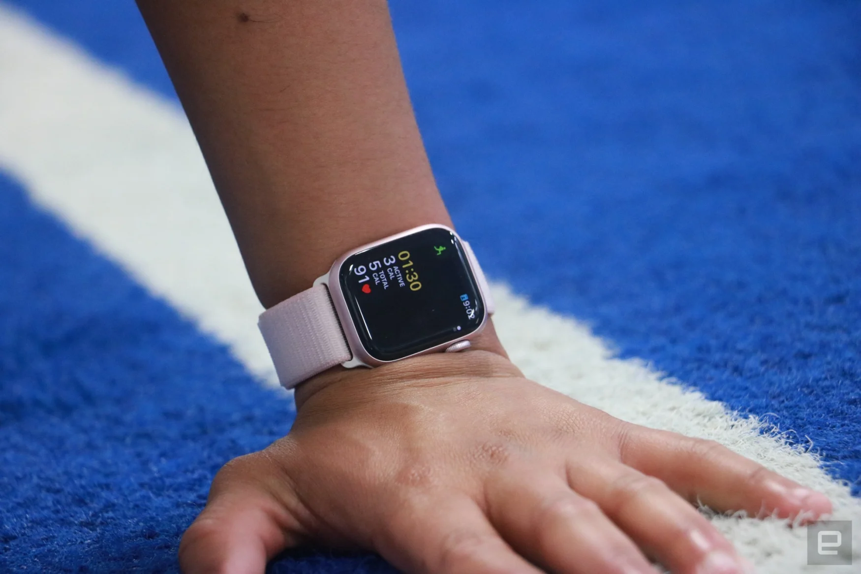 The Apple Watch Series 9 on a person's wrist, with the hand placed on a blue-and-white track.