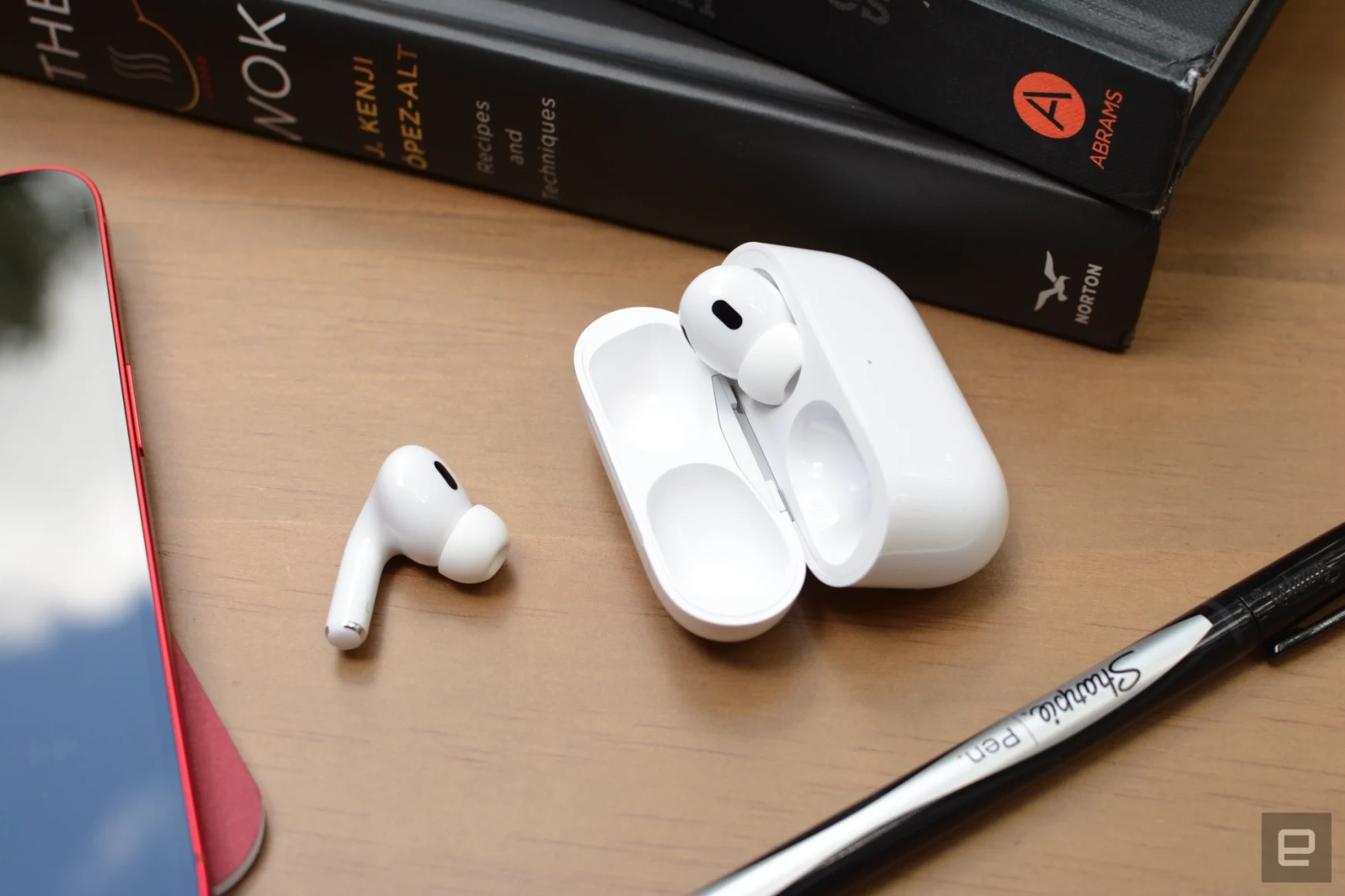 Photo of AirPods Pro (second-gen) on a desk with a pen and books