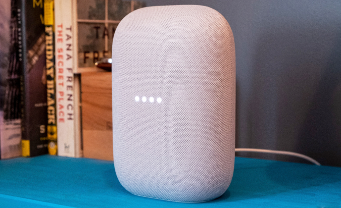 The Google Nest Audio smart speaker sitting on a blue table.