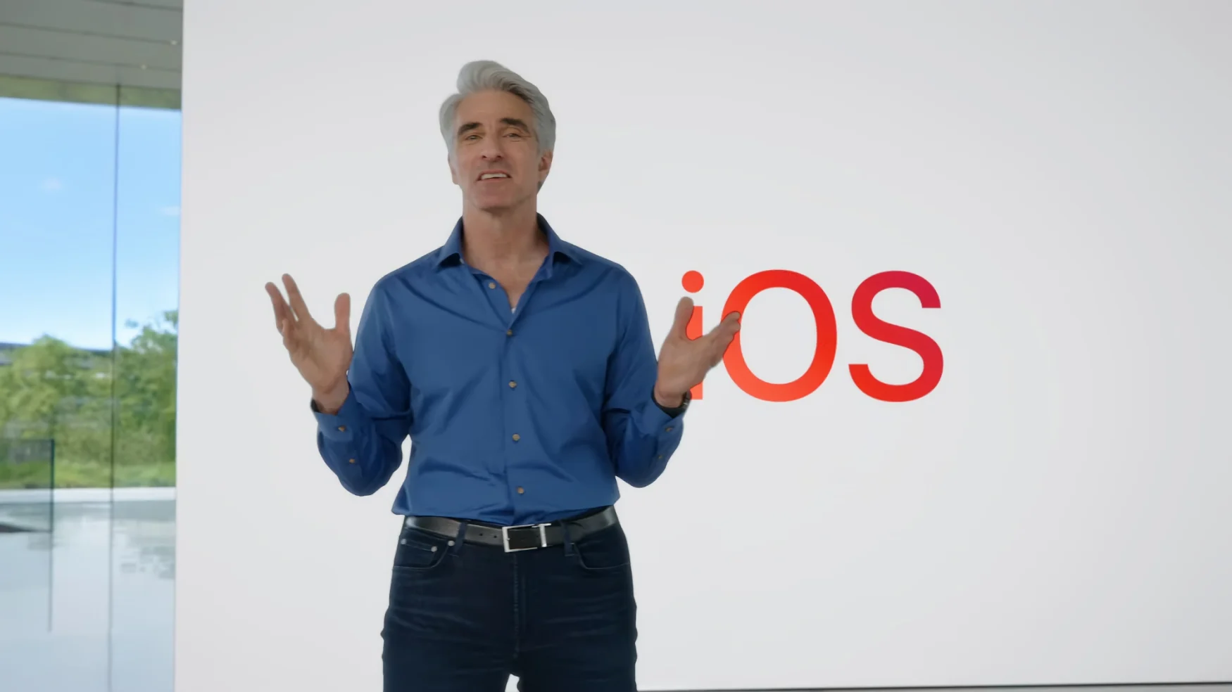 Apple VP Craig Federighi at the WWDC keynote event. He stands inside Apple Park in front of a huge white board that reads 