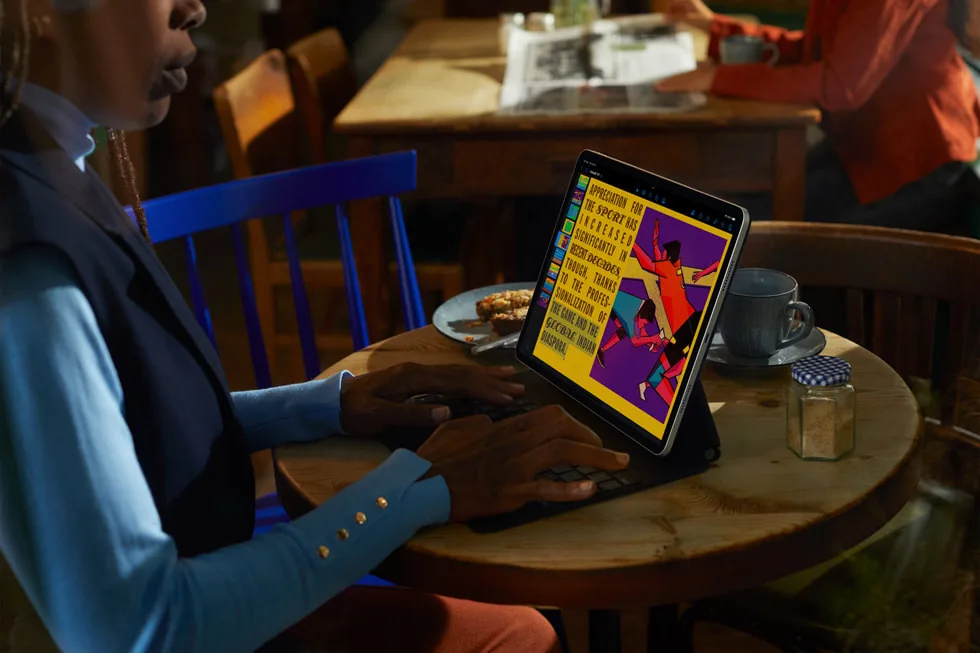 A person uses an iPad Pro while sitting at a table.