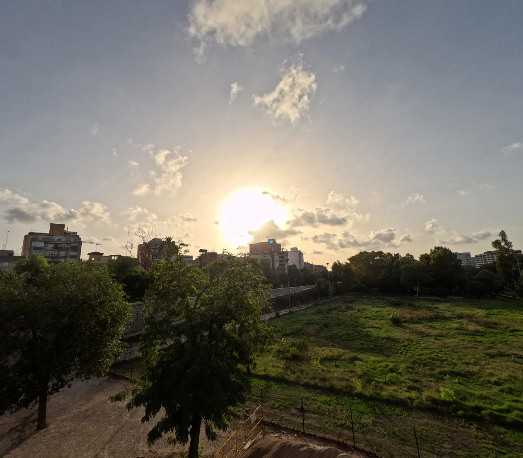 A photo of a setting sun over a park area in a city center.