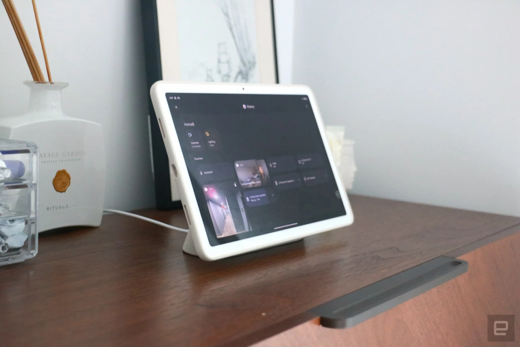 The Pixel Tablet on a walnut dresser showing the smart home dashboard in Hub Mode.