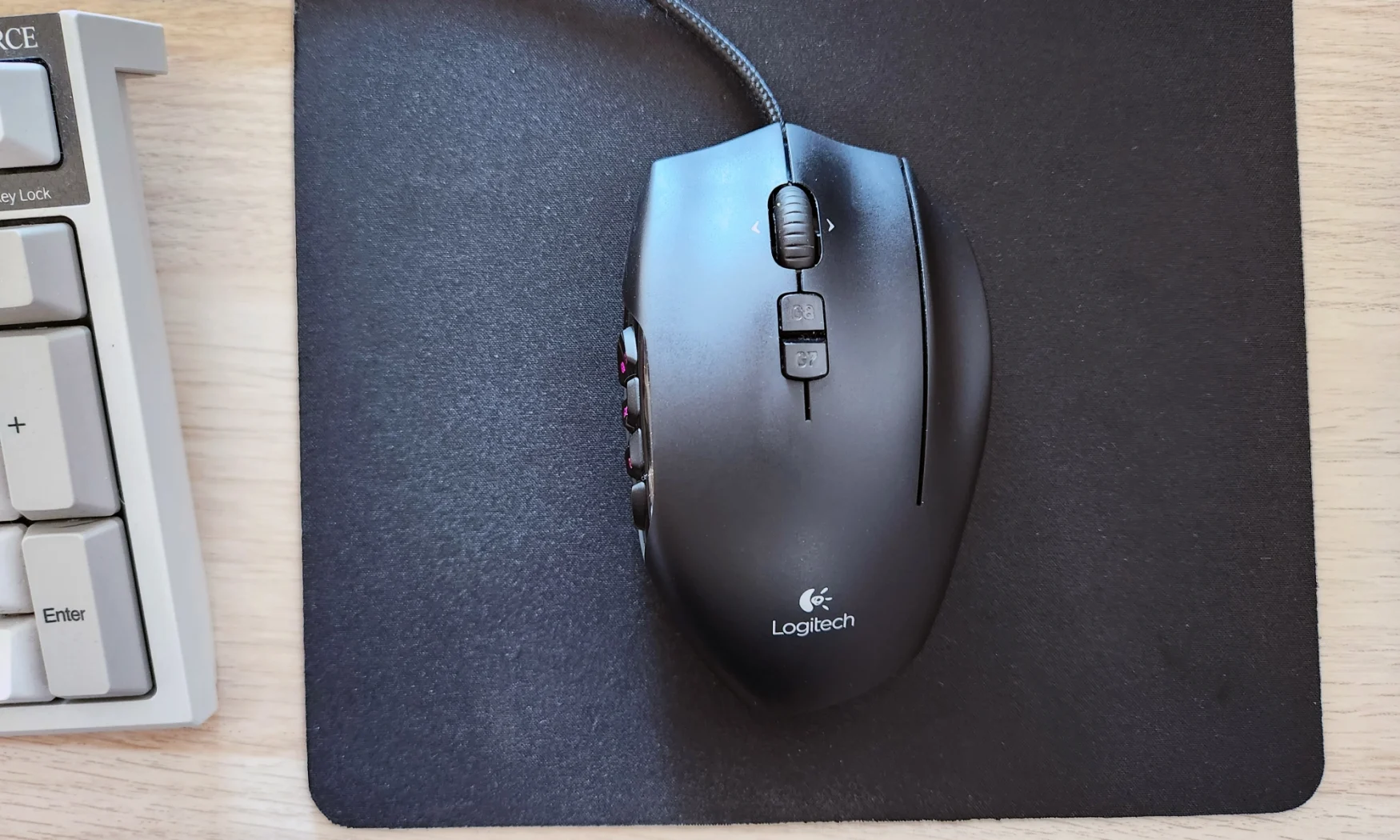 The Logitech G600 MMO gaming mouse rested on top of a black mouse pad on a desk.