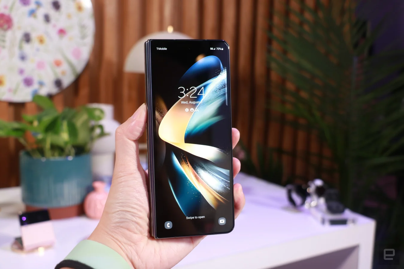 A hand holding up a closed Galaxy Z Fold 4 with its external display facing the camera.