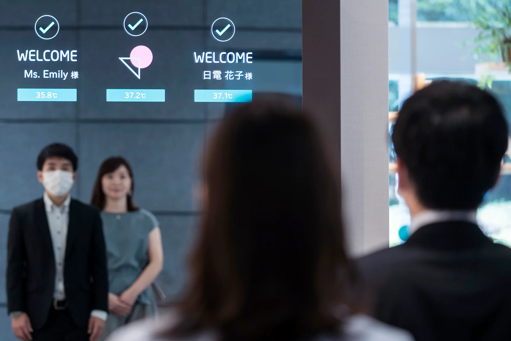 TOKYO, JAPAN - JULY 13: Employees stand in front of a monitor during a demonstration of the smart gateless and touchless entrance that allows temperature checks and face recognition for masked faces at the NEC Corporation headquarters on July 13, 2020 in Tokyo, Japan. NEC Corporation has transformed its Tokyo headquarters skyscraper into a smart building to showcase its "new normal" technologies and services to facilitate worker safety and organizational efficiency for the post COVID-19 world. (Photo by Tomohiro Ohsumi/Getty Images for NEC Corporation)
