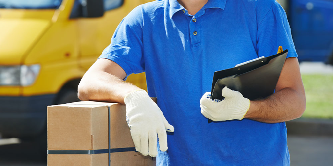 Stock image of a male delivery person in gloves holding a clipboard, photographed from the neck down.