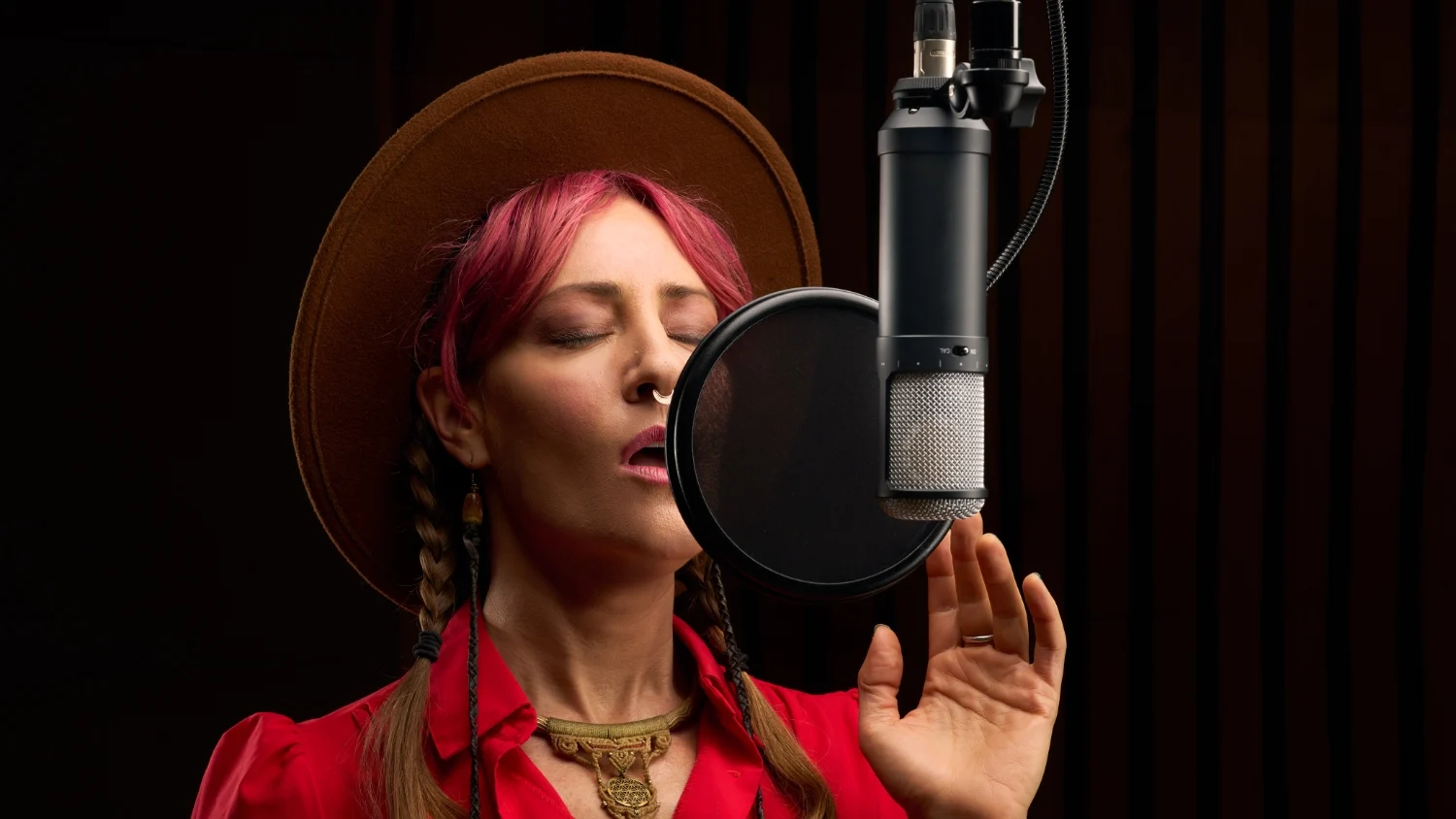 Una cantante en un estudio con los ojos cerrados cantando en el micrófono UA Sphere LX