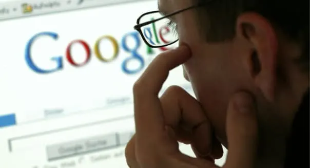 Man in front of a display with the website of the internet search engine Google.