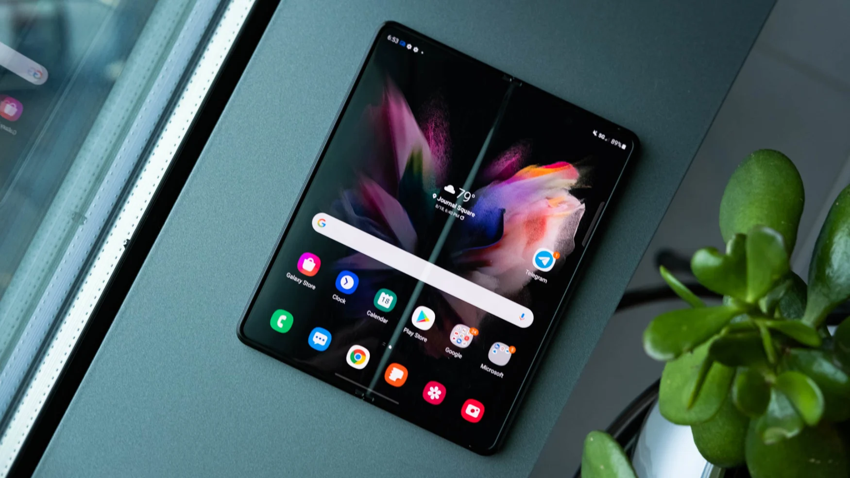 The Samsung Galaxy Z Fold 3 laying open, flat on its back, on a window ledge.