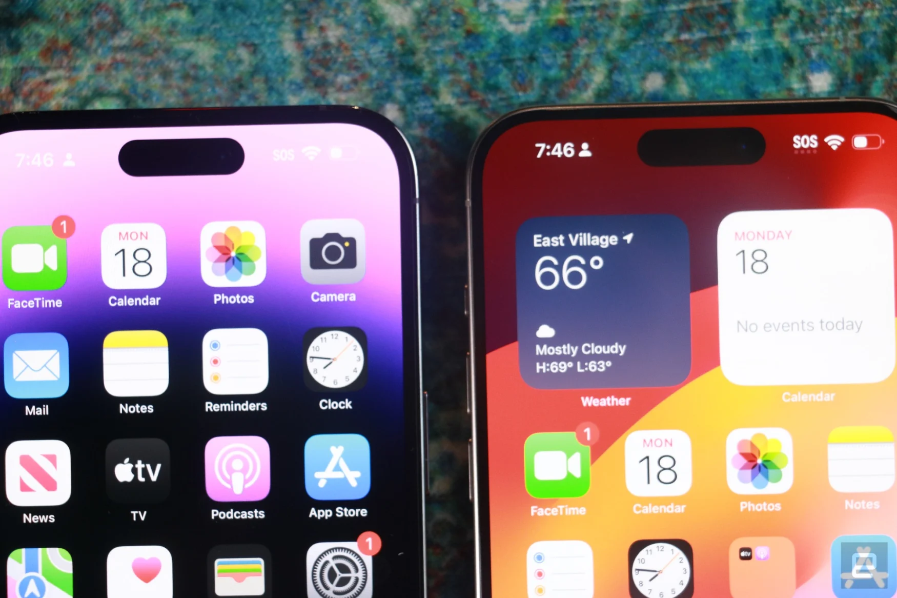 The iPhone 15 Pro Max and iPhone 14 Pro Max side by side, closed up on their displays. The bezels on the iPhone 14 Pro, which is on the left, are slightly thicker. 