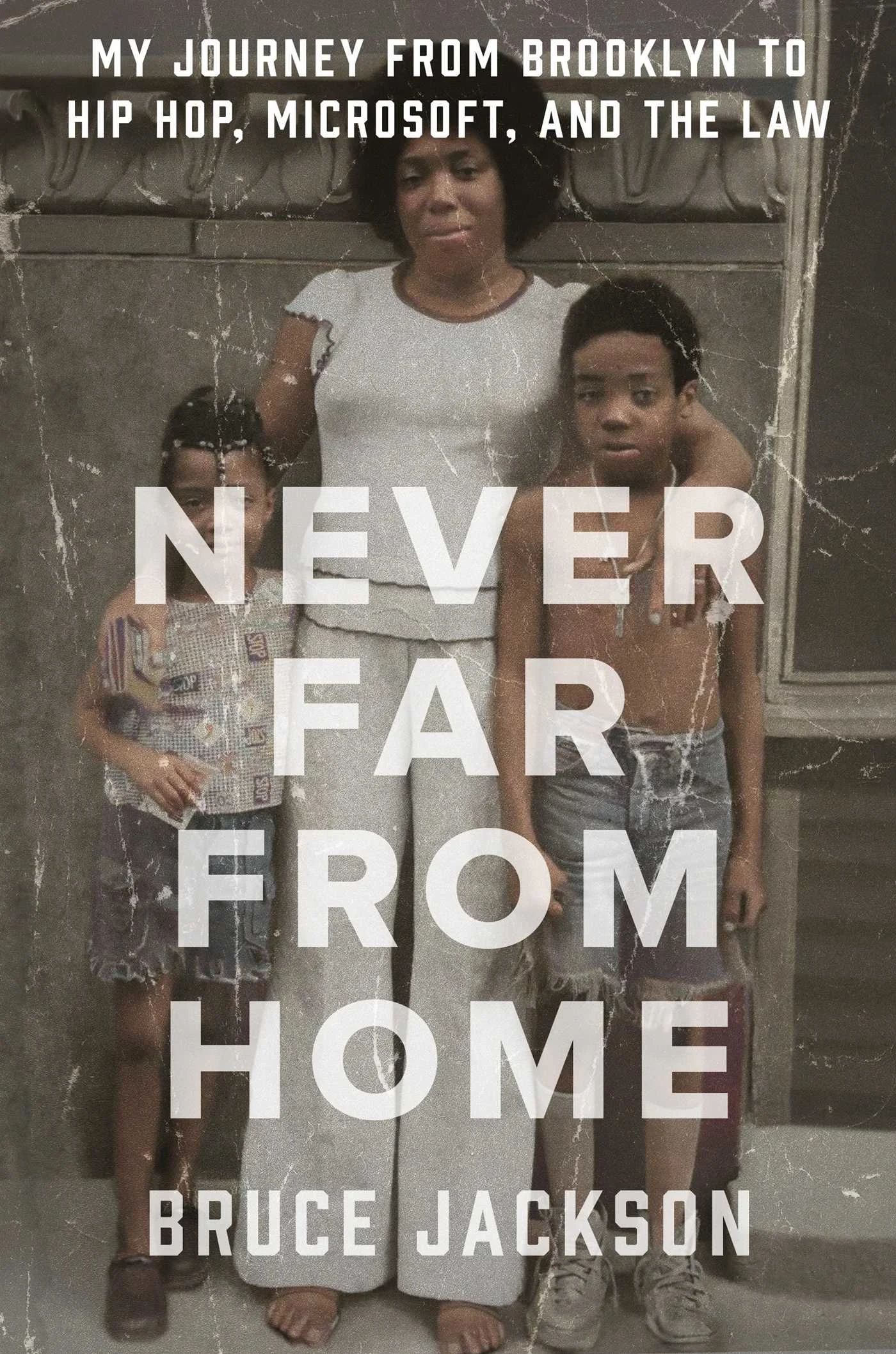 background is full-fill of a creased picture of a black woman standing in front of a grey wall, each of her arms draped around the shoulders of two boys (elementary school aged). Looks like a family snapshot taken in the late 70s/early 80s.  Title and author name in all caps white lettering atop.  