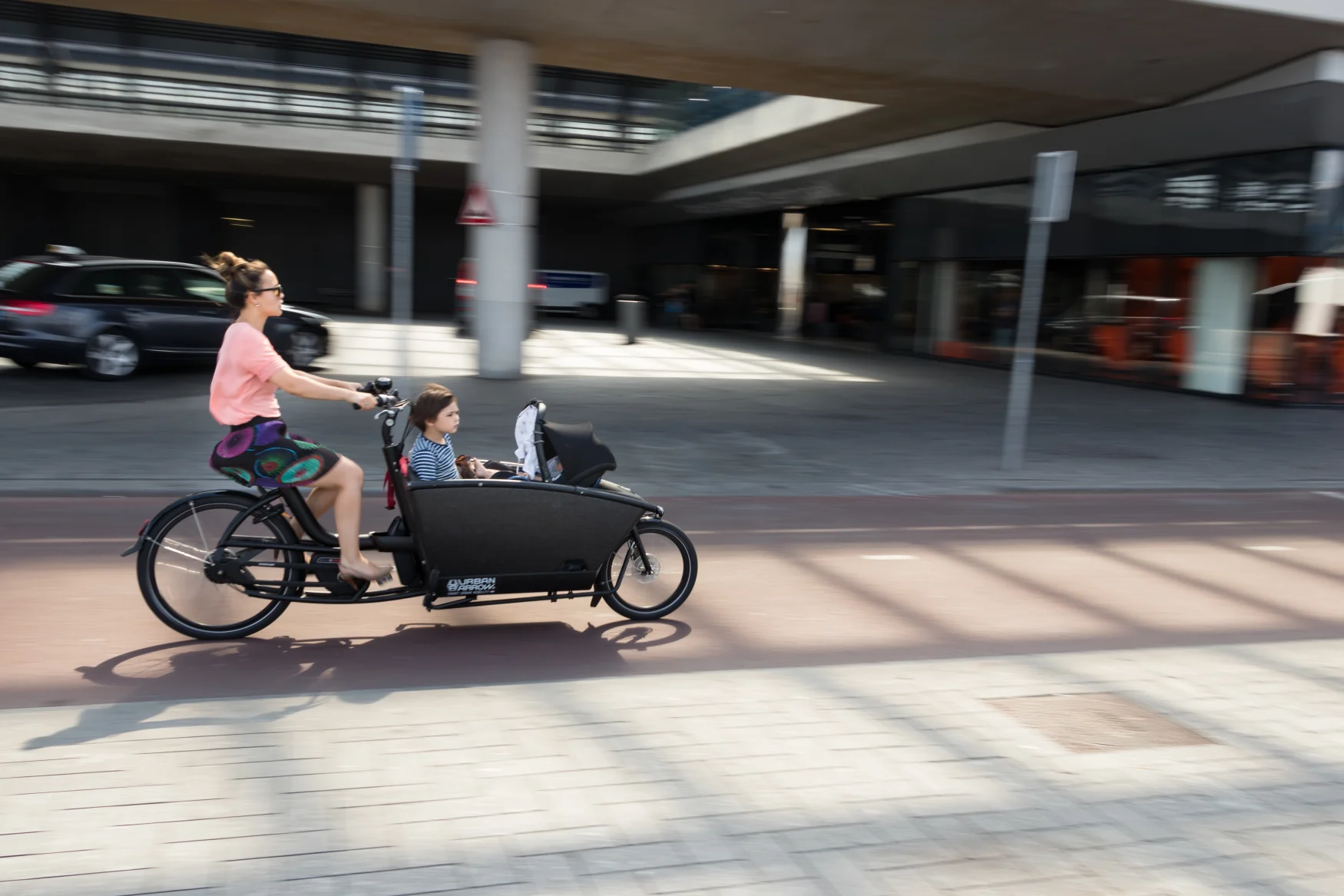 Amsterdam, Netherland - July 20th, 2018: A woman cycling with kids on a cargo bike at the Amsterdam Central Train Station, Netherlands.