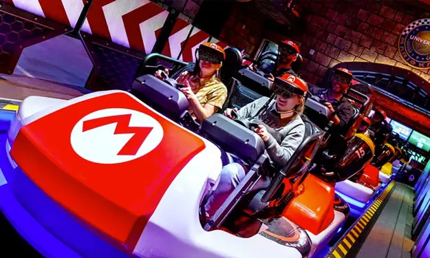 Image of riders wearing AR headsets on the Mario Kart-themed ride at Nintendo's theme park.