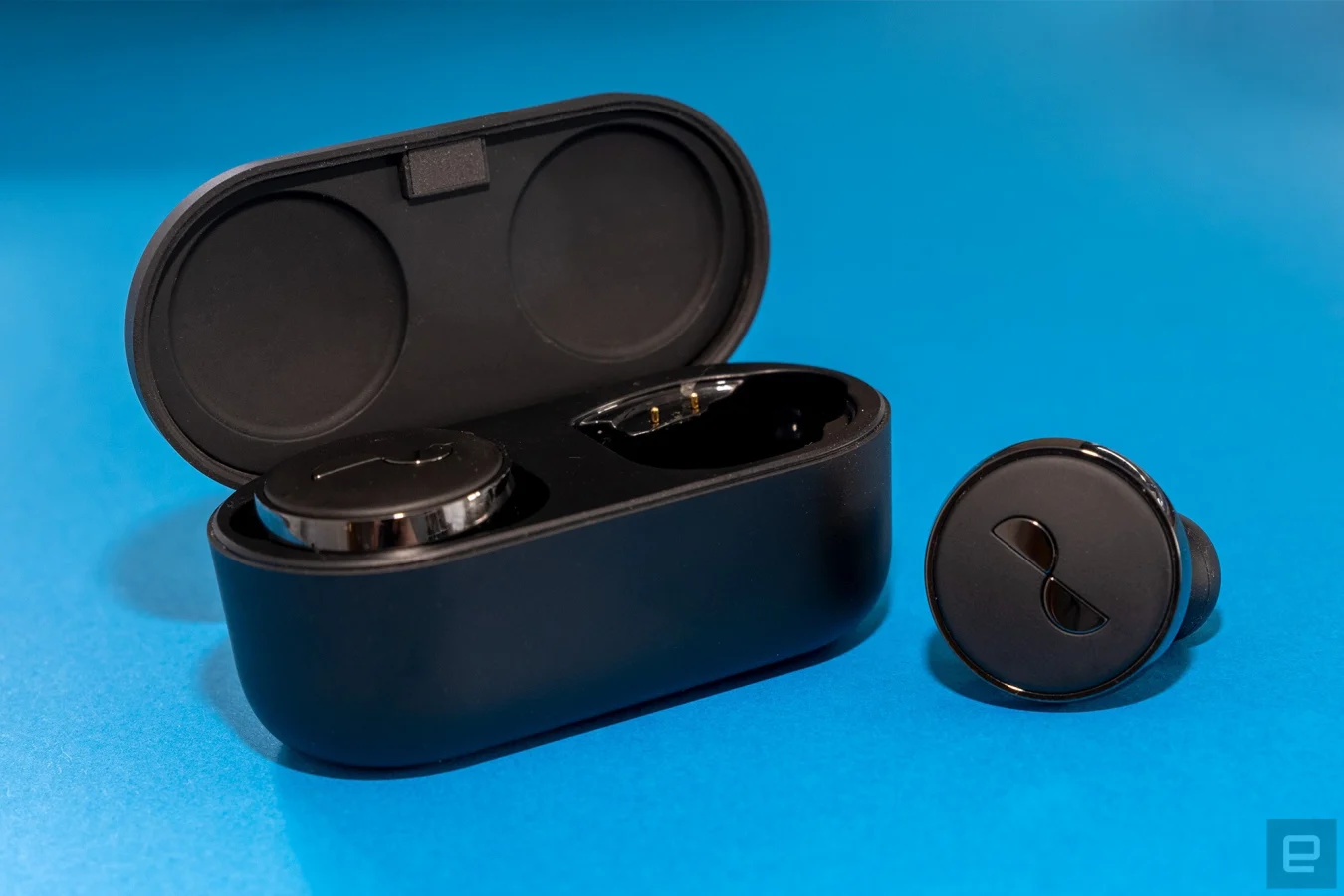 One NuraTrue earbud is pictured beside the charging case.