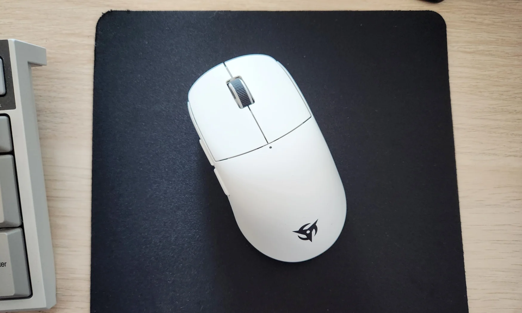 A white gaming mouse called the Ninjutso Sora rested on top of a black mouse pad on a desk.
