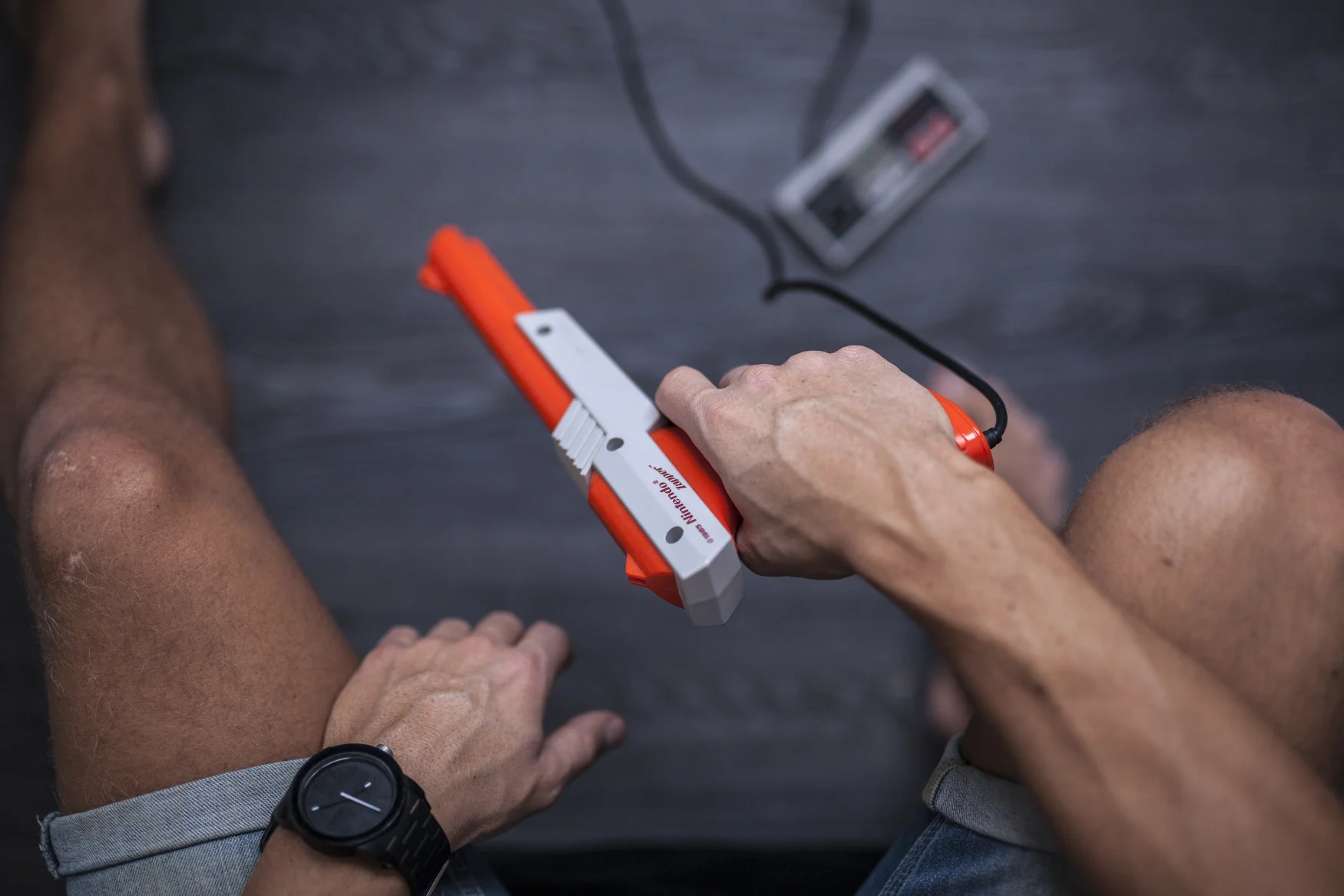 Gothenburg, Sweden - January 31, 2015: A shot from above of a young man's hands using a 1985 Nintendo Zapper, a remote game controller for the Nintendo Entertainment System developed by Nintendo Co., Ltd. in the 1980s. His hands are posing casually as he is resting between games. Natural lighting. Shot on a grey wooden background.