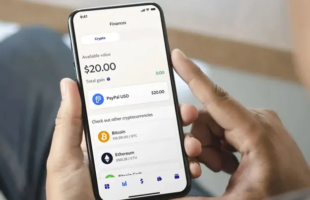 Image of a device with the PayPal app open showing a list of cryptocurrencies including PayPal USD, the company's new stablecoin.