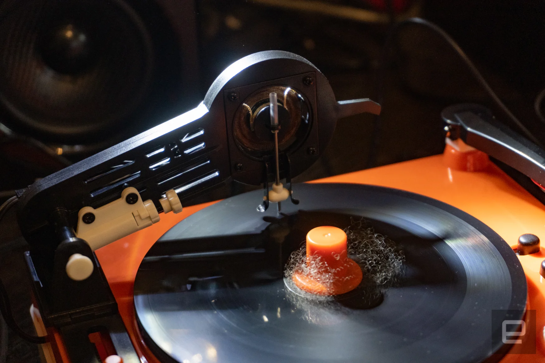 A turntable with an arm that ends in a cutter, touching a black disc.