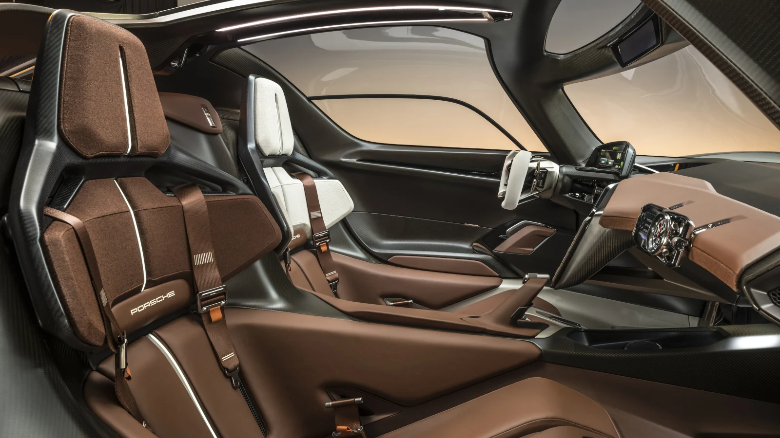The interior of the Porsche Mission X concept showing its brown leather seats, open-top steering wheel and large windows.