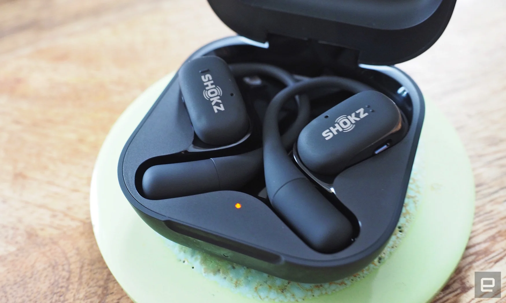 Close-up images of the Shokz OpenFit open-back headphones in gray with the charging case.