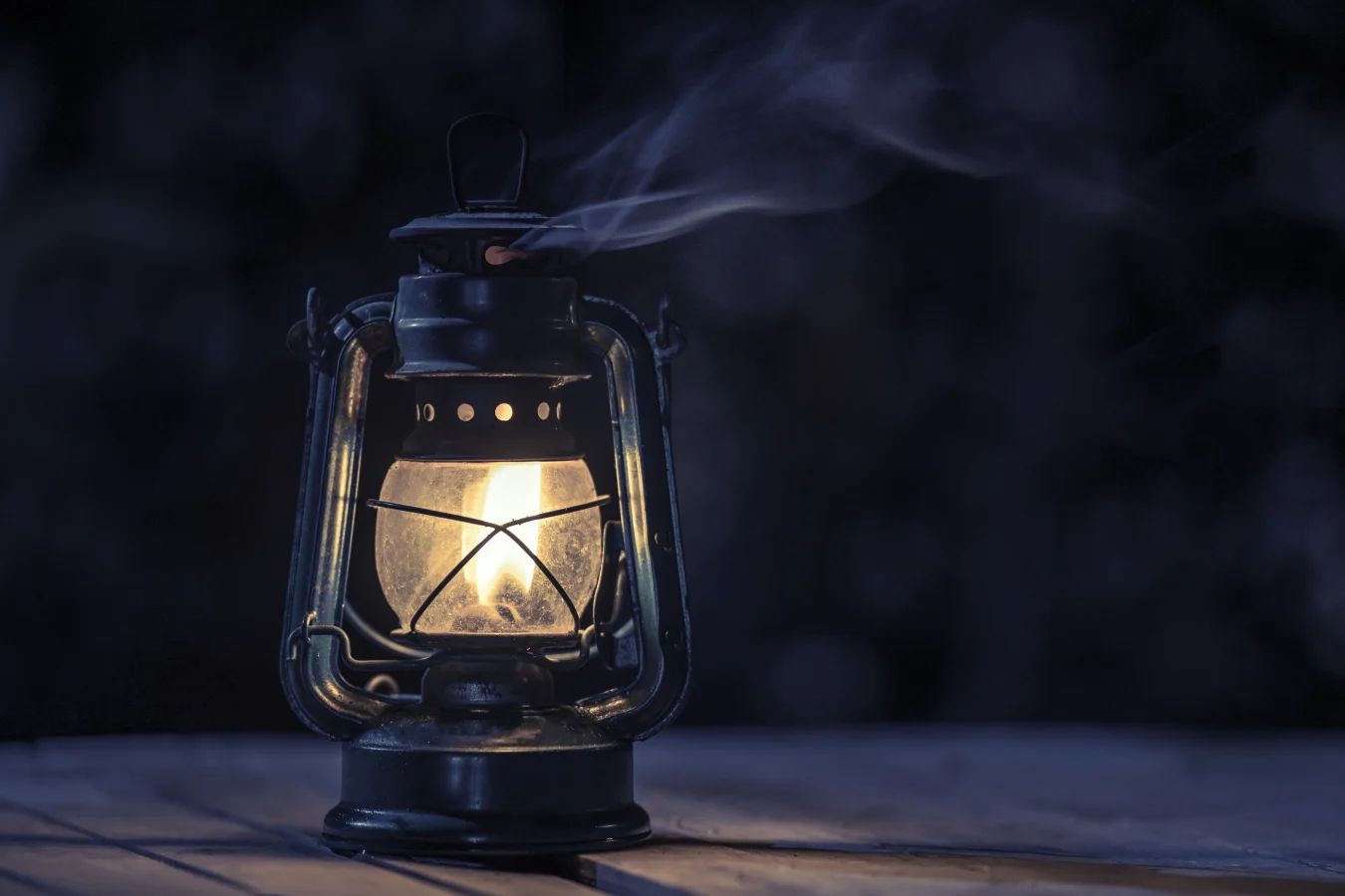 antique kerosene lamp with lights on the wooden floor on the lawn at night