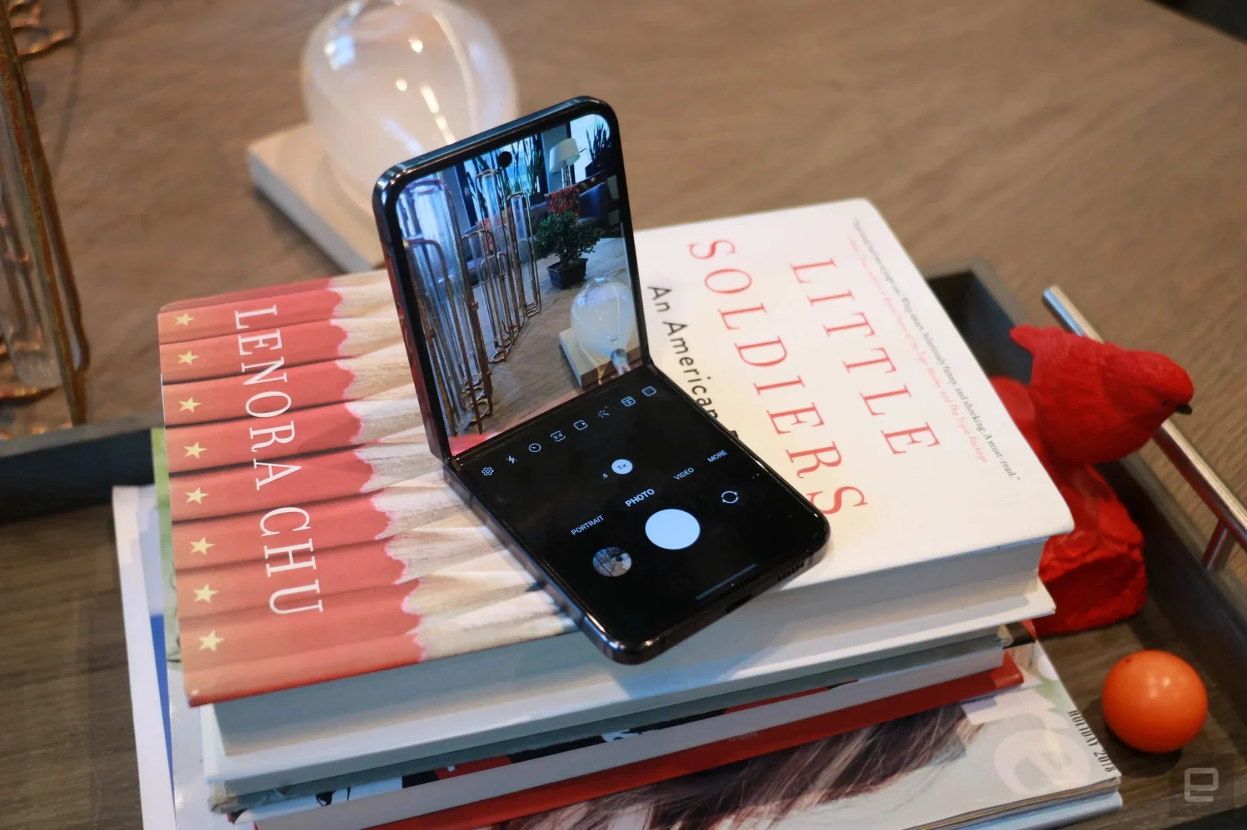 A Samsung Z Flip 5 foldable phone sitting on a pile of books (the top book is 