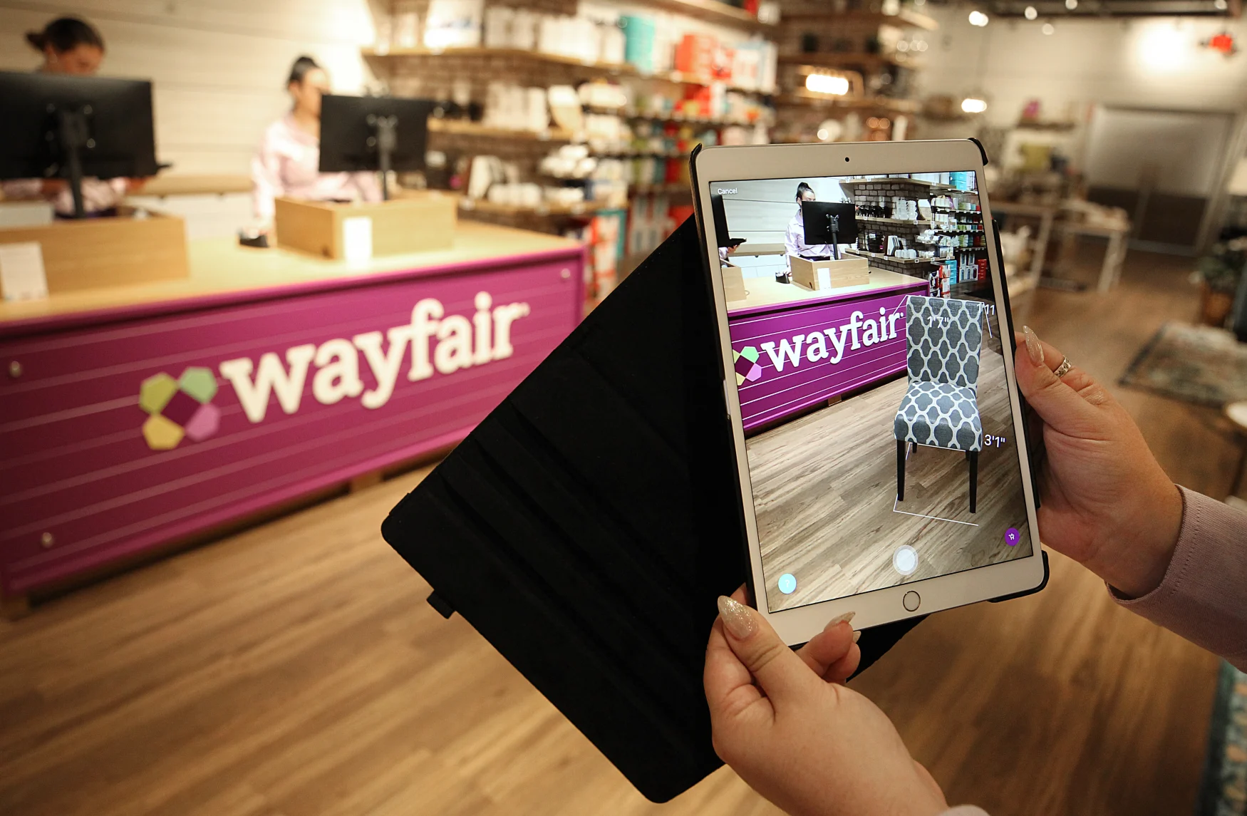 NATICK, MA - AUGUST 20: A virtual reality app is demonstrated at Wayfair's first store in the Natick Mall in Natick, MA on Aug. 20, 2019. Shoppers can don virtual reality headsets to see how furniture would fit into a space, using Wayfairs Room Planner tool. They can virtually climb onto a dining room table to get a 360-degree view of a digitally rendered room, then swap out chairs, chandeliers, and art on the virtual walls. Thats just one example of how the Boston-based e-commerce giant has used its digital DNA to create its first brick-and-mortar store. It opens Wednesday in the Natick Mall. Product information, including prices and customer ratings, is displayed on screens that update in real time to reflect online price changes. Staffers carry iPads with an augmented reality tool that makes furniture appear in a 3-D setting, or they can snap a picture of an item in the store and find dozens like it online. (Photo by Suzanne Kreiter/The Boston Globe via Getty Images)