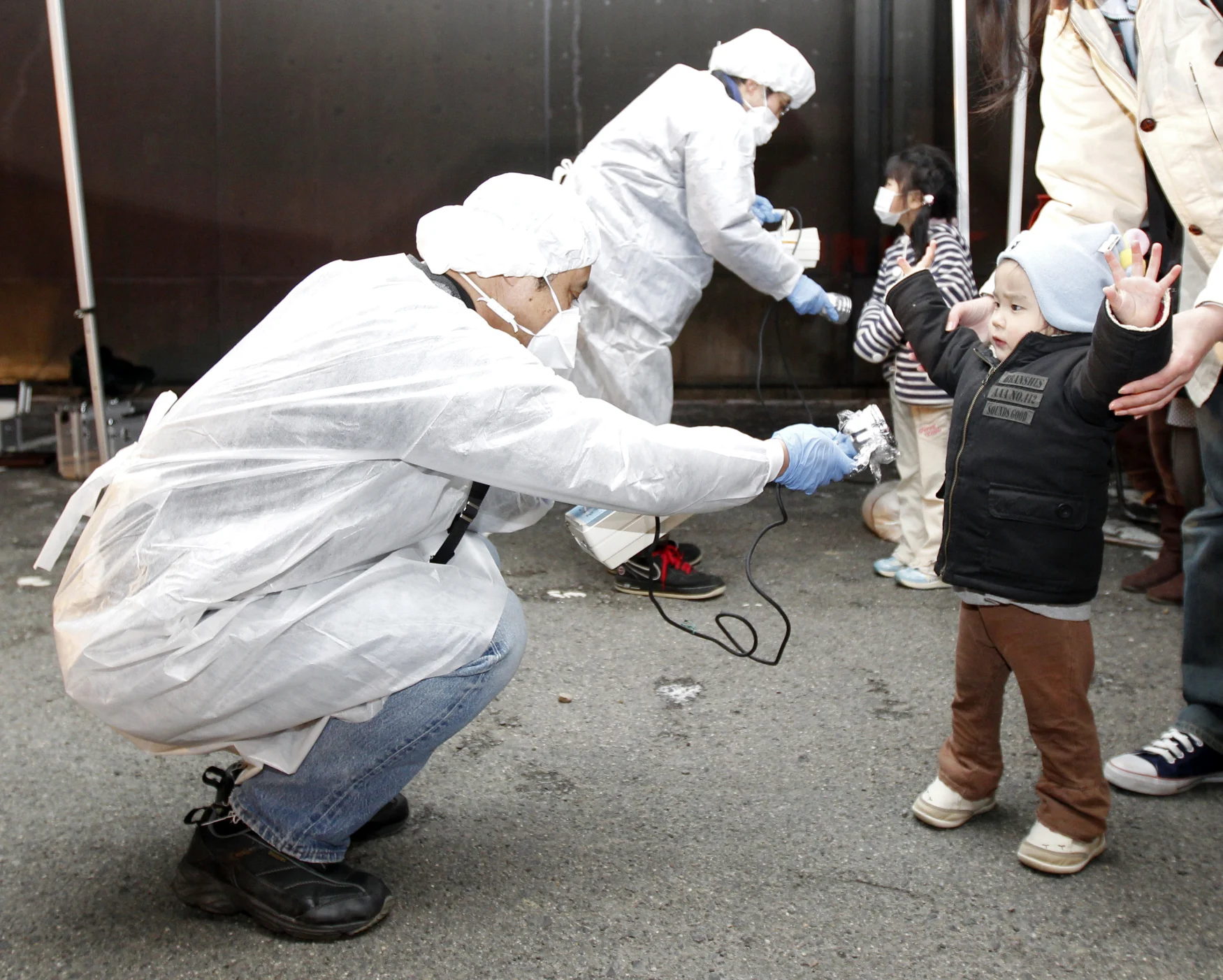 Officials in protective gear check for signs of radiation on children who are from the evacuation area near the Fukushima Daini nuclear plant in Koriyama, March 13, 2011. Japanese Chief Cabinet Secretary Yukio Edano confirmed on Saturday there has been an explosion and radiation leakage at Tokyo Electric Power Co's (TEPCO) Fukushima Daiichi nuclear power plant. The biggest earthquake to hit Japan on record struck the northeast coast on Friday, triggering a 10-metre tsunami that swept away everything in its path, including houses, ships, cars and farm buildings on fire.   REUTERS/Kim Kyung-Hoon (JAPAN - Tags: DISASTER ENVIRONMENT ENERGY IMAGES OF THE DAY)   FOR BEST QUALITY IMAGE: ALSO SEE GF2E88U0STU01.