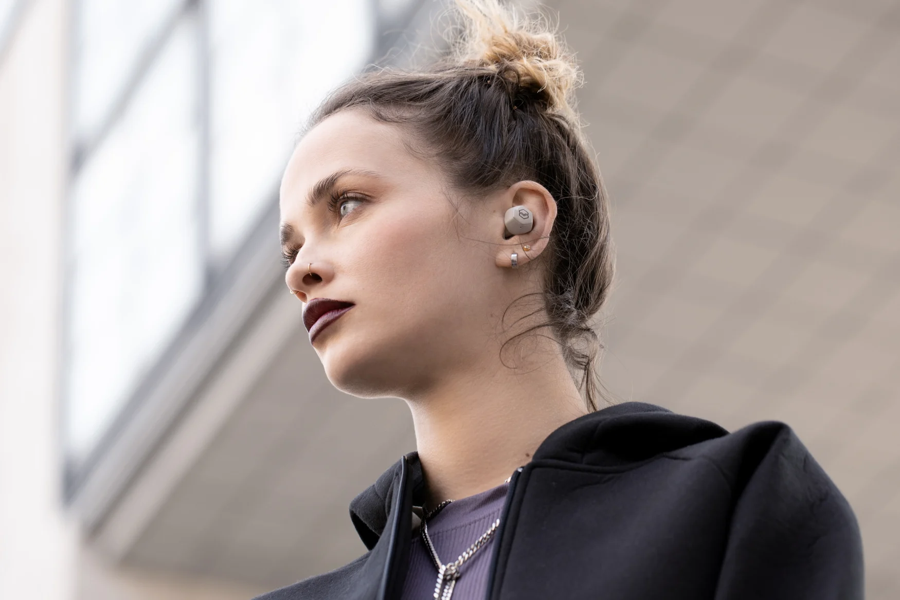 A model wearing a white version of V-Moda's Hexamove Lite earbuds