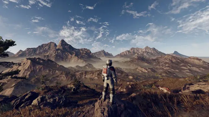 Promotional image of the game 'Starfield', featuring a spacesuited figure looking out on a wild vista of rocky mountains. 