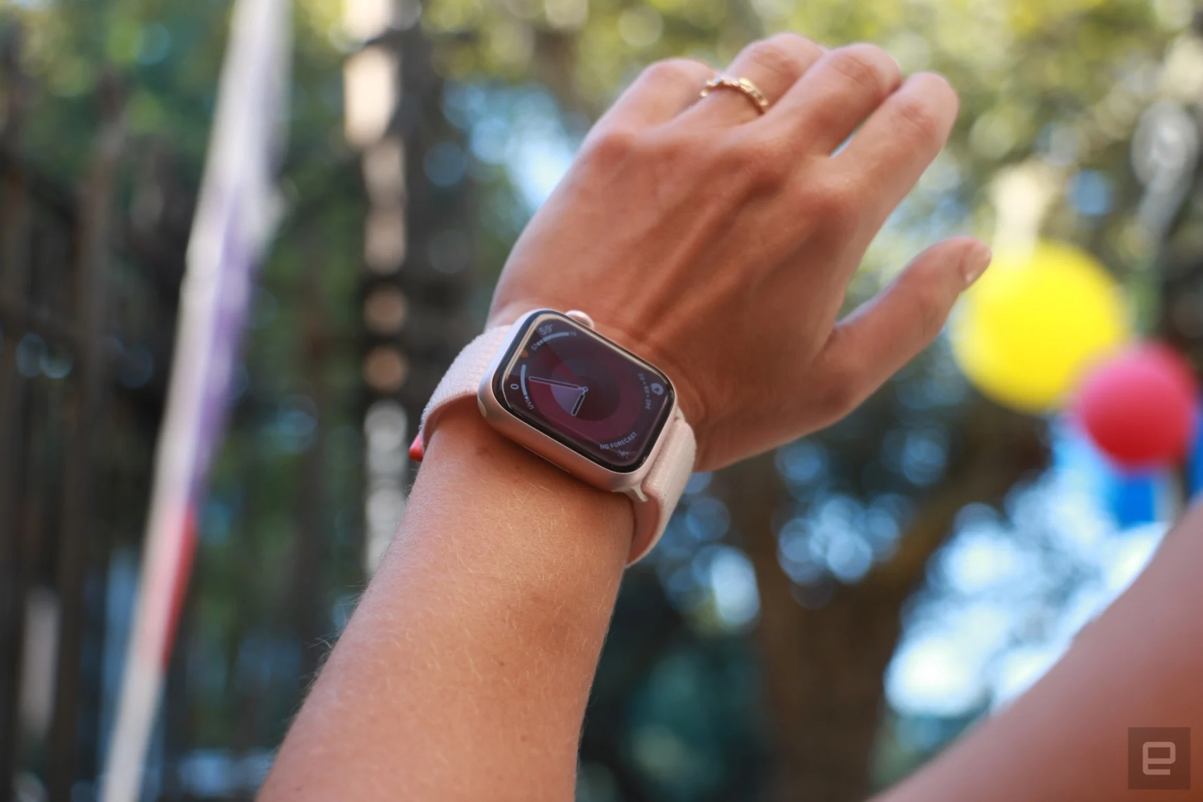 The Apple Watch Series 9 on a wrist in mid-air, with some balloons in the blurred background.
