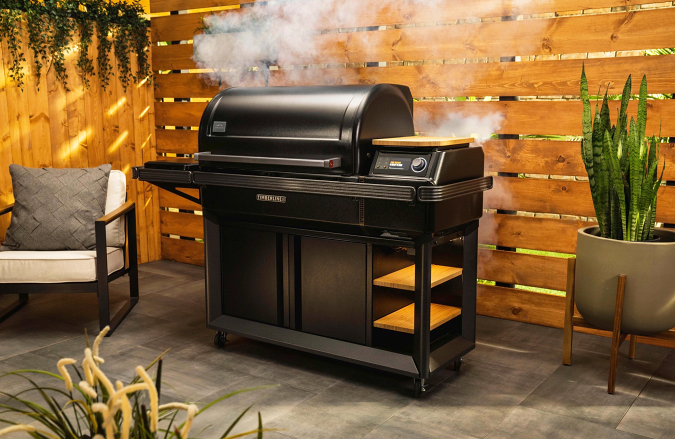 Traeger Timberline grill on a patio surrounded by a wood fence.