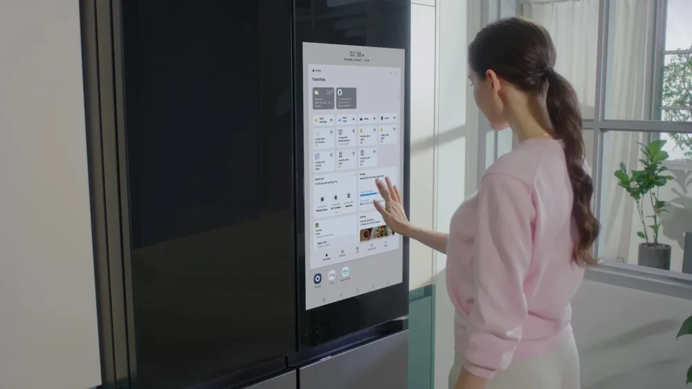 A person uses the Family Hub+ touchscreen on Samsung's 4-Door Flex fridge.